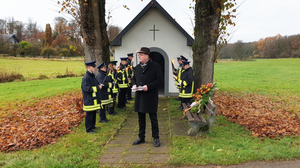 Ehrenformation der freiwilligen Feuerwehr vor der Kapelle in Krümmel. Im Vordergrund, Ortsbürgermeister Burkhard Kuhn bei seiner Ansprache.